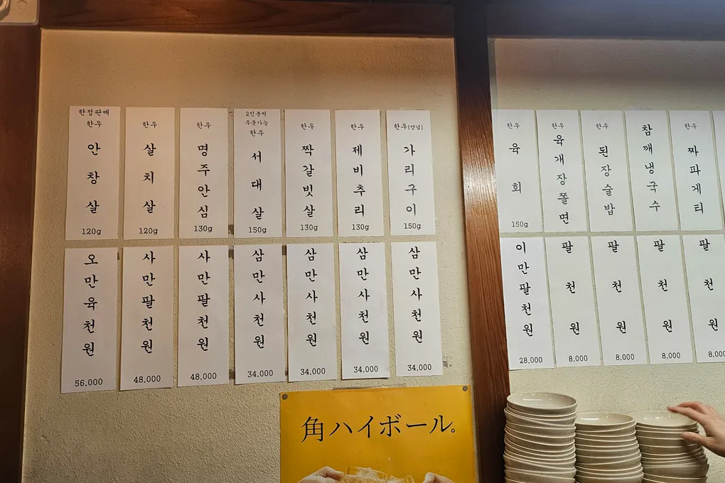 A wall price board at Baeksong listing hanwoo cuts and prices in Korean won