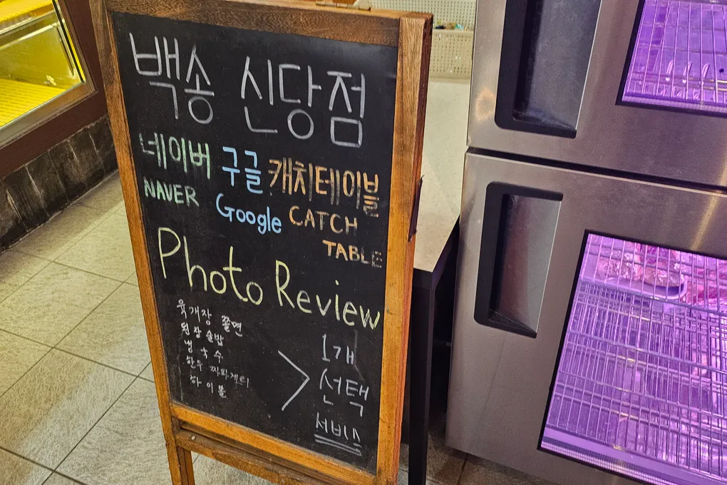 A chalkboard at Baeksong promoting Naver, Google, and CatchTable photo reviews