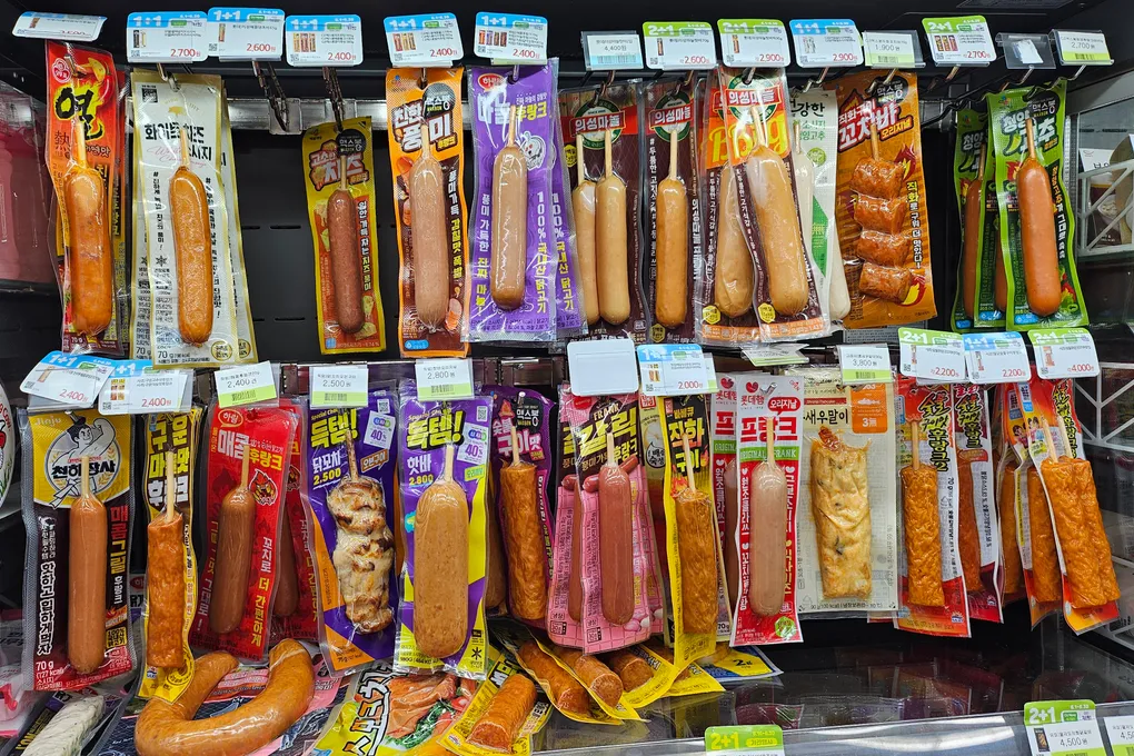 A wall of packaged sausages and hotbar sticks at a Korean convenience store