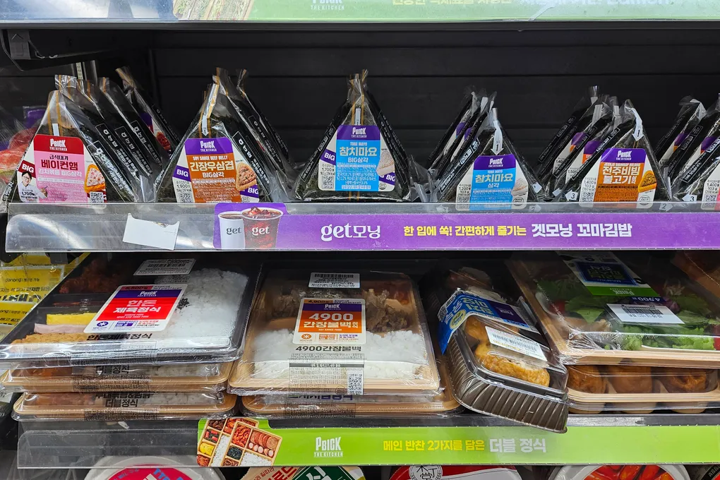 Triangle kimbap and gimbap rolls on a refrigerated shelf at a Korean convenience store
