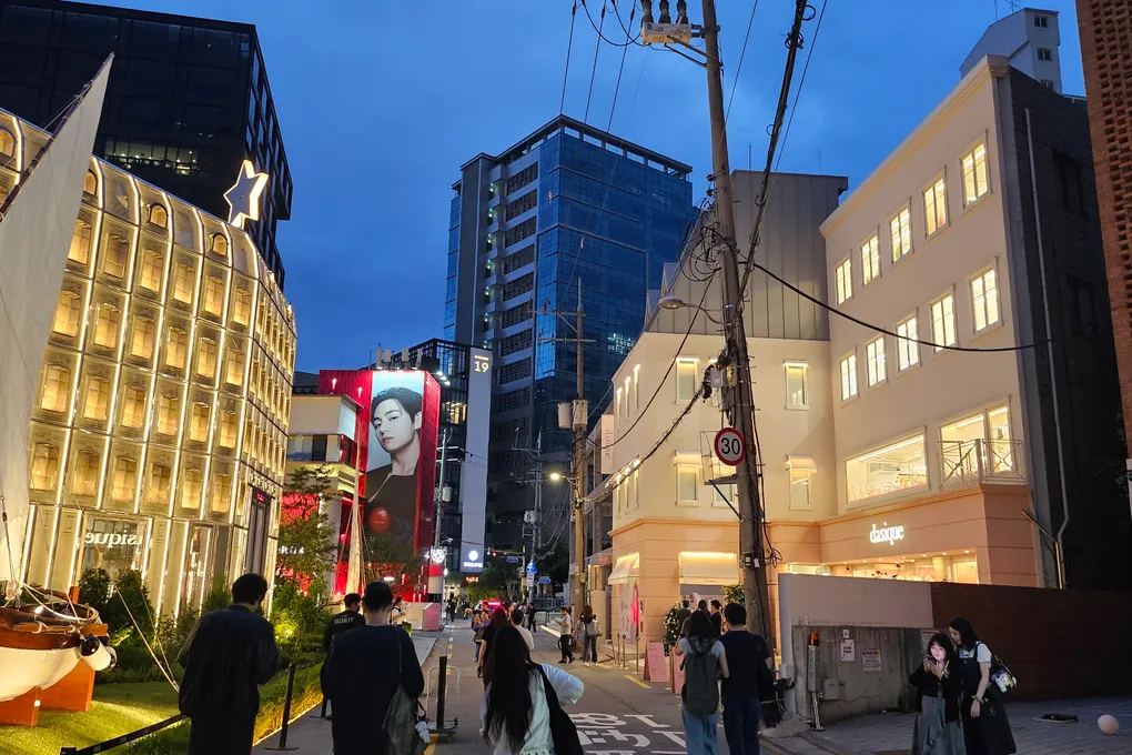 Dior Seongsu glowing golden building with a sailboat installation and crowds in the evening