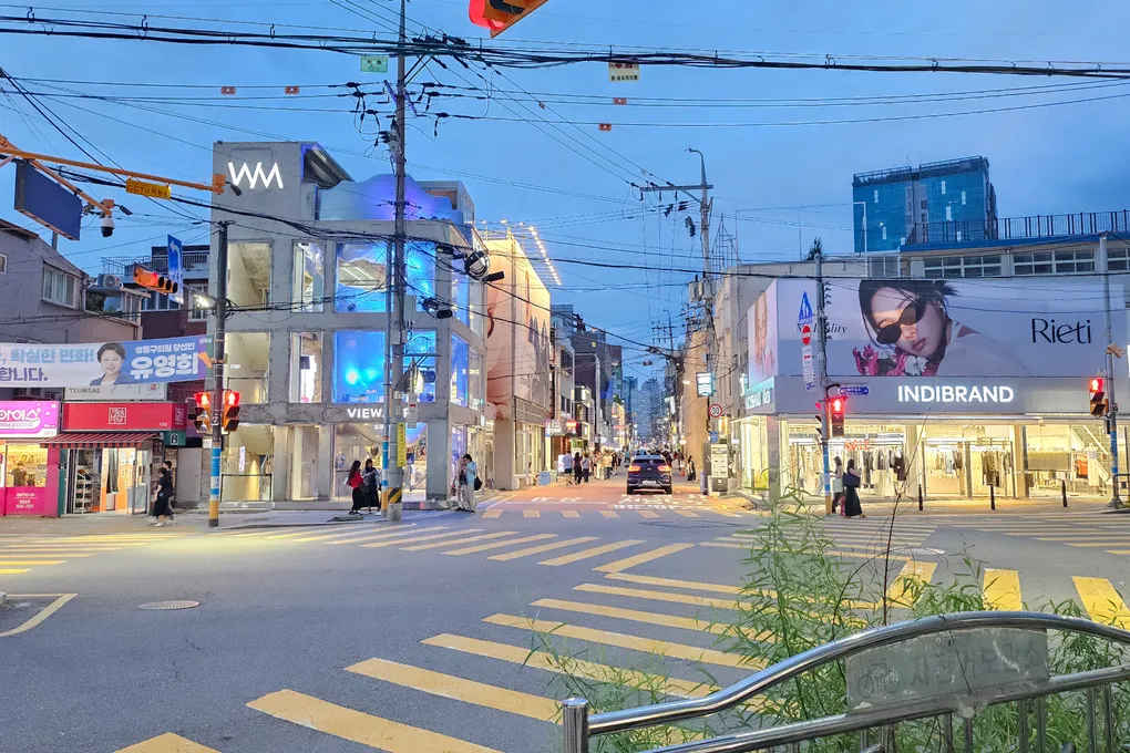 The entrance to Yeonmujang-gil street in Seongsu at blue hour, with fashion brand buildings and a crosswalk