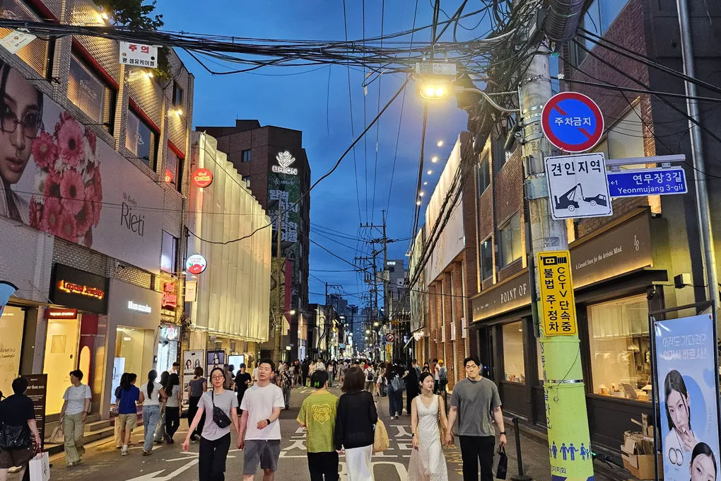 A busy evening crowd walking down Yeonmujang-gil in Seongsu with neon shop signs