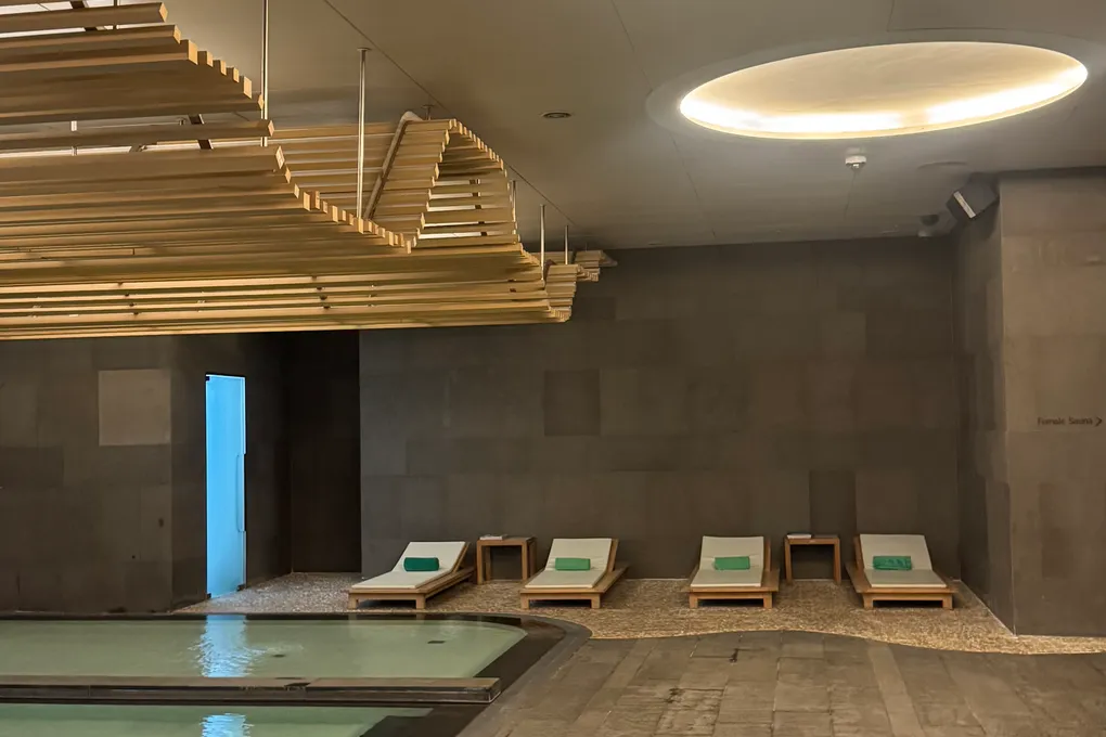 Indoor swimming pool at Banyan Tree Seoul under a sculptural slatted wooden ceiling with sun loungers