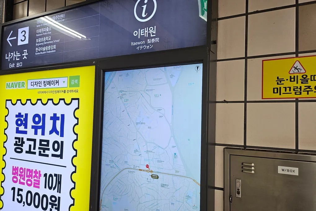 Itaewon Station name sign in four languages next to a lit area map