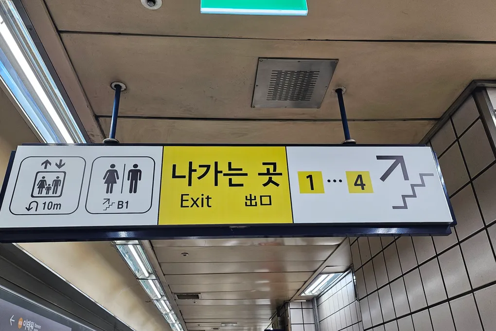 Overhead exit sign in a Seoul subway station pointing to exits 1 through 4, in Korean and English