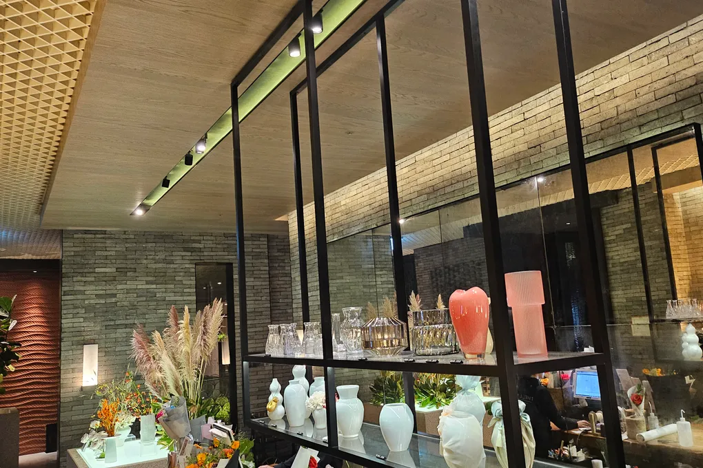 The entrance area outside Teppan with a black-framed glass display case holding glassware and vases, dried pampas grass, and a brick wall